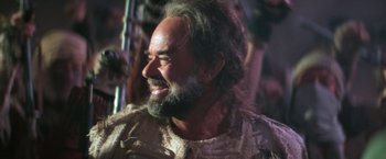 Movie still from “Star Trek V: The Final Frontier” (1989), directed by William Shatner – A man with long hair and a beard smiling for the camera; Close Up shot, Over the shoulder angle