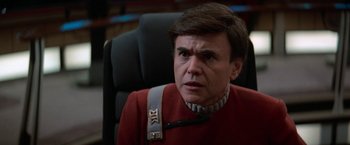 Movie still from “Star Trek V: The Final Frontier” (1989), directed by William Shatner – A man in a red shirt is sitting in a chair; Close Up shot, Over the shoulder angle