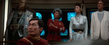 Movie still from “Star Trek V: The Final Frontier” (1989), directed by William Shatner – A group of people standing next to each other in a room; Medium shot, Over the shoulder angle