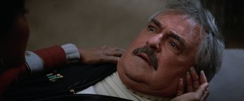 Movie still from “Star Trek V: The Final Frontier” (1989), directed by William Shatner – An older man with a mustache is getting his hair combed; Close Up shot, Low angle
