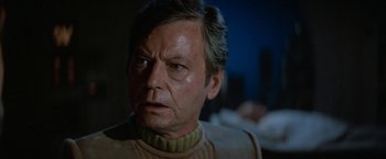 Movie still from “Star Trek V: The Final Frontier” (1989), directed by William Shatner – An older man in a tan sweater stares at the camera; Close Up shot, Over the shoulder angle