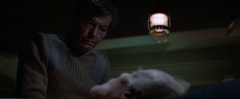 Movie still from “Star Trek V: The Final Frontier” (1989), directed by William Shatner – An older man is looking at a white dog; Close Up shot, Over the shoulder angle