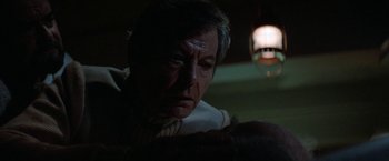 Movie still from “Star Trek V: The Final Frontier” (1989), directed by William Shatner – An older man is looking down at a lamp; Close Up shot, Over the shoulder angle