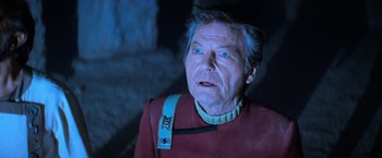 Movie still from “Star Trek V: The Final Frontier” (1989), directed by William Shatner – An older man wearing a red shirt and a blue neck tie; Close Up shot, Low angle