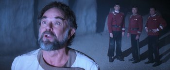 Movie still from “Star Trek V: The Final Frontier” (1989), directed by William Shatner – A man with a beard wearing a red uniform; Close Up shot, Over the shoulder angle