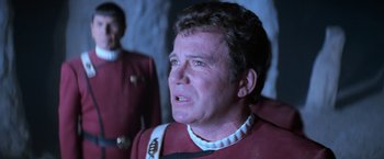 Movie still from “Star Trek V: The Final Frontier” (1989), directed by William Shatner – A person wearing a red and white uniform; Close Up shot, Over the shoulder angle