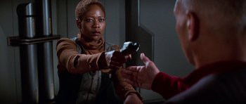 Movie still from “Star Trek: First Contact” (1996), directed by Jonathan Frakes – A woman holding a gun in her hand while a man holds out his hand; Medium shot, Over the shoulder angle
