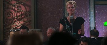 Movie still from “Star Trek: First Contact” (1996), directed by Jonathan Frakes – A woman standing at a microphone in front of an audience; Medium shot, Over the shoulder angle