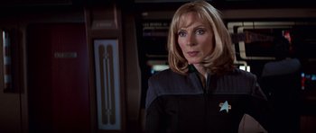 Movie still from “Star Trek: First Contact” (1996), directed by Jonathan Frakes – A woman with blonde hair wearing a black and blue uniform; Close Up shot, Over the shoulder angle