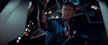 Movie still from “Star Trek: First Contact” (1996), directed by Jonathan Frakes – A man in a tie and a hat is holding something up; Close Up shot, Over the shoulder angle