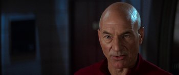 Movie still from “Star Trek: First Contact” (1996), directed by Jonathan Frakes – A man with a shaved head and a red shirt; Close Up shot, Over the shoulder angle