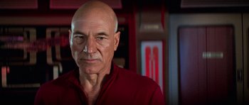 Movie still from “Star Trek: First Contact” (1996), directed by Jonathan Frakes – An older man in a red shirt is looking at the camera; Close Up shot, Low angle