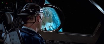 Movie still from “Star Trek: First Contact” (1996), directed by Jonathan Frakes – A man with a headset looking out a window at the earth from space; Medium shot, Over the shoulder angle