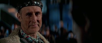 Movie still from “Star Trek: First Contact” (1996), directed by Jonathan Frakes – An older man wearing a head dress and smiling for the camera; Close Up shot, Over the shoulder angle