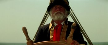 Movie still from “Star Trek: Generations” (1994), directed by David Carson – An older man in a suit and tie holding a steering wheel; Close Up shot, Low angle