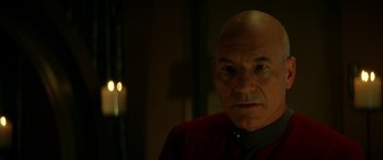 Movie still from “Star Trek: Generations” (1994), directed by David Carson – A man with a bald head wearing a red shirt; Close Up shot, Over the shoulder angle