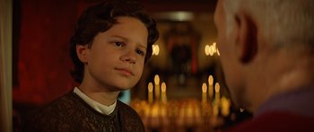 Movie still from “Star Trek: Generations” (1994), directed by David Carson – A young boy is looking at the camera in front of candles in a church; Close Up shot, Over the shoulder angle
