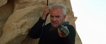 Movie still from “Star Trek: Generations” (1994), directed by David Carson – A man holding a cell phone while standing next to a rock wall; Close Up shot, Low angle