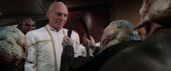 Movie still from “Star Trek: Insurrection” (1998), directed by Jonathan Frakes – A man is holding a pair of gloves while another man is holding a pair of gloves; Close Up shot, Over the shoulder angle