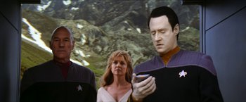 Movie still from “Star Trek: Insurrection” (1998), directed by Jonathan Frakes – Two men and a woman looking at a cell phone; Medium shot, Over the shoulder angle