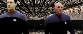 Movie still from “Star Trek: Insurrection” (1998), directed by Jonathan Frakes – Two men standing next to each other in front of a building; Medium shot, Low angle