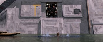Movie still from “Star Trek: Insurrection” (1998), directed by Jonathan Frakes – A woman swimming in a body of water with two men standing in the background; Extreme Wide shot, High angle