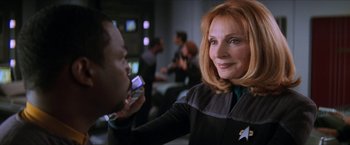 Movie still from “Star Trek: Insurrection” (1998), directed by Jonathan Frakes – A woman is talking on a cell phone while a man is looking on; Close Up shot, Over the shoulder angle