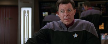 Movie still from “Star Trek: Insurrection” (1998), directed by Jonathan Frakes – A person wearing a star trek uniform; Close Up shot, Over the shoulder angle