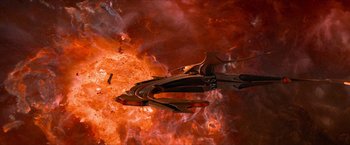 Movie still from “Star Trek: Insurrection” (1998), directed by Jonathan Frakes – An image of a space ship in the middle of a fire; Extreme Wide shot, Overhead angle