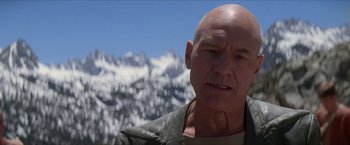 Movie still from “Star Trek: Insurrection” (1998), directed by Jonathan Frakes – A bald man in front of a snowy mountain; Close Up shot, Low angle