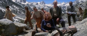 Movie still from “Star Trek: Insurrection” (1998), directed by Jonathan Frakes – A woman sitting on the ground while holding a cell phone; Wide shot, Low angle