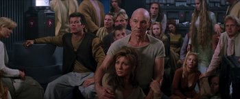 Movie still from “Star Trek: Insurrection” (1998), directed by Jonathan Frakes – A group of people sitting in front of each other in a room; Medium shot, Over the shoulder angle