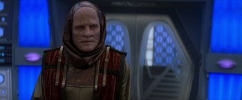 Movie still from “Star Trek: Insurrection” (1998), directed by Jonathan Frakes – A man with a red and brown head covering; Close Up shot, Over the shoulder angle
