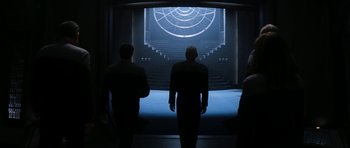 Movie still from “Star Trek: Nemesis” (2002), directed by Stuart Baird – Three men are standing in front of an empty stage; Wide shot, Over the shoulder angle