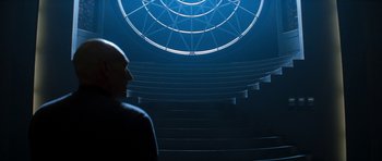 Movie still from “Star Trek: Nemesis” (2002), directed by Stuart Baird – A man standing in front of a circular staircase; Wide shot, Low angle