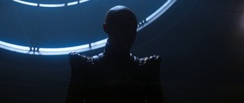 Movie still from “Star Trek: Nemesis” (2002), directed by Stuart Baird – A man with a bald head is standing in front of a clock; Medium shot, Over the shoulder angle