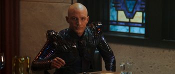 Movie still from “Star Trek: Nemesis” (2002), directed by Stuart Baird – A bald man in a leather jacket sitting at a table; Medium shot, Over the shoulder angle