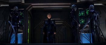 Movie still from “Star Trek: Nemesis” (2002), directed by Stuart Baird – A man and a woman dressed in black standing in front of a building; Wide shot, Low angle