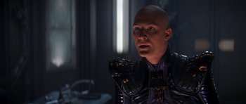 Movie still from “Star Trek: Nemesis” (2002), directed by Stuart Baird – A bald man in a black and purple outfit; Close Up shot, Over the shoulder angle