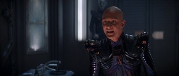 Movie still from “Star Trek: Nemesis” (2002), directed by Stuart Baird – A bald man in a black and purple outfit; Medium shot, Over the shoulder angle