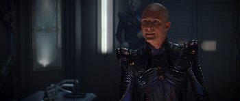 Movie still from “Star Trek: Nemesis” (2002), directed by Stuart Baird – A bald man in a black and purple outfit; Medium shot, Over the shoulder angle