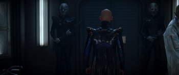 Movie still from “Star Trek: Nemesis” (2002), directed by Stuart Baird – A man in a black and blue suit standing next to another man in a black and blue suit; Medium shot, Over the shoulder angle