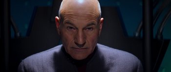 Movie still from “Star Trek: Nemesis” (2002), directed by Stuart Baird – An older man with a bald head and a smirk on his face; Close Up shot, Low angle
