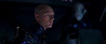 Movie still from “Star Trek: Nemesis” (2002), directed by Stuart Baird – A bald man in a blue suit looking to his left; Close Up shot, Low angle