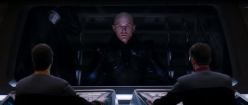 Movie still from “Star Trek: Nemesis” (2002), directed by Stuart Baird – A bald man in a black jacket is looking at the camera; Medium shot, Low angle