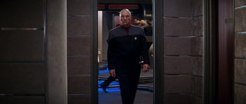 Movie still from “Star Trek: Nemesis” (2002), directed by Stuart Baird – A man in a uniform is walking through a doorway; Medium shot, Over the shoulder angle