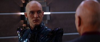 Movie still from “Star Trek: Nemesis” (2002), directed by Stuart Baird – A man with a bald head wearing a black outfit; Close Up shot, Over the shoulder angle