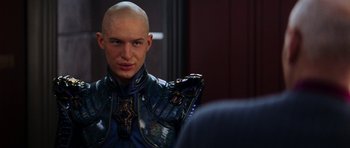 Movie still from “Star Trek: Nemesis” (2002), directed by Stuart Baird – A man with a bald head wearing a suit of armor; Close Up shot, Over the shoulder angle