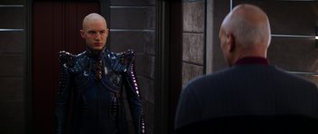 Movie still from “Star Trek: Nemesis” (2002), directed by Stuart Baird – A bald man in a suit is looking at himself in the mirror; Medium shot, Over the shoulder angle