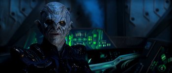 Movie still from “Star Trek: Nemesis” (2002), directed by Stuart Baird – An image of an alien in a room with lights in the background; Close Up shot, Over the shoulder angle